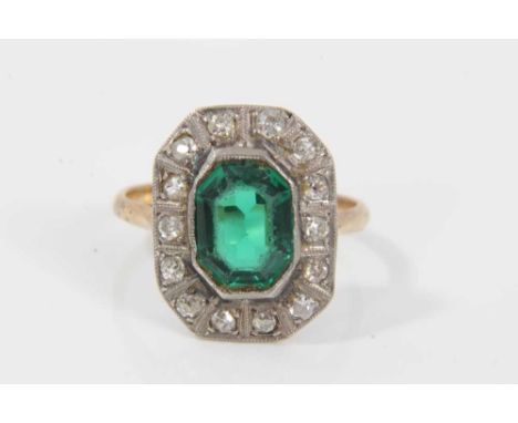 1920s diamond and green stone cocktail ring with a step cut green stone surrounded by a border of old cut and single cut diam