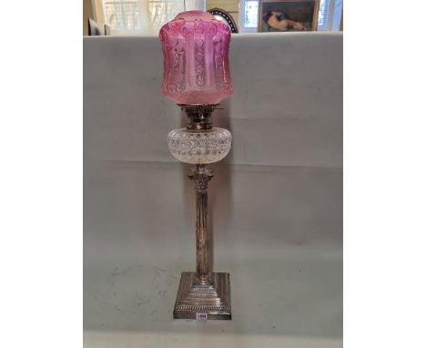 A good electroplated Corinthian column oil lamp, with cut glass reservoir and cranberry glass shade, height excluding chimney