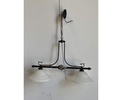 A twin ceiling pendent light fitting, the patinated scrolled metal frame supporting two domed frosted glass shades, complete 