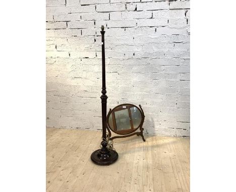 A Georgian century mahogany framed vanity mirror, the oval mirror swiveling between scrolled uprights and raised on four spla