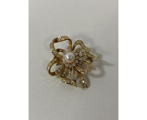 An 18ct gold diamond and pearl ribbon style brooch measures 3.5cm wide weighs 8.6grammes