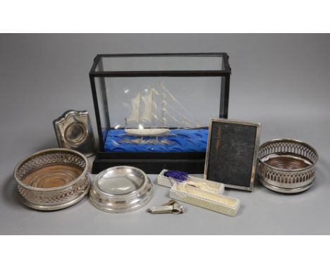 A group of silver and white metal items including a cased boat model, cigar cutter and mounted photograph frame and plated it