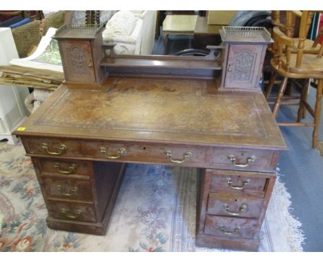 A late Victorian oak twin pedestal writing desk, extended back with single shelf, flanked by glove boxes having Art Nouveau d