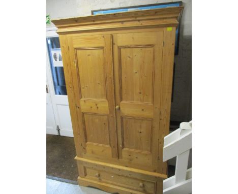 A modern pine wardrobe with a pair of panelled doors, over a long drawer, raised on a bracket plinth, 78 h, 45 w