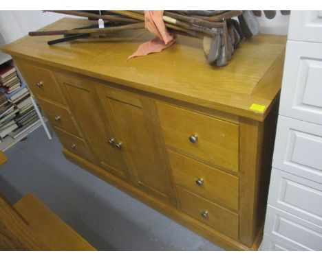 A modern light oak sideboard having twin cupboard doors, six short drawers, standing on a plinth base, 33 1/4 h x 54w