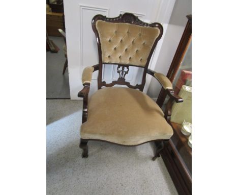 A Victorian mahogany green fabric upholstered armchair with carved button back on French cabriole legs and ceramic castors