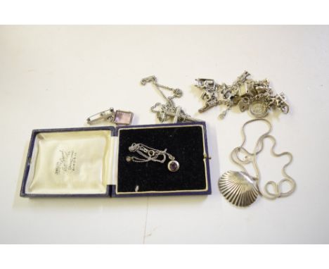 A silver charm bracelet hung with various charms; a white metal cross pendant; a Sterling silver scallop brooch etc. 