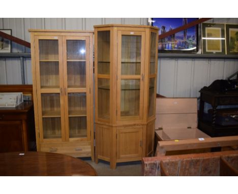 A light oak and glazed corner cabinet 