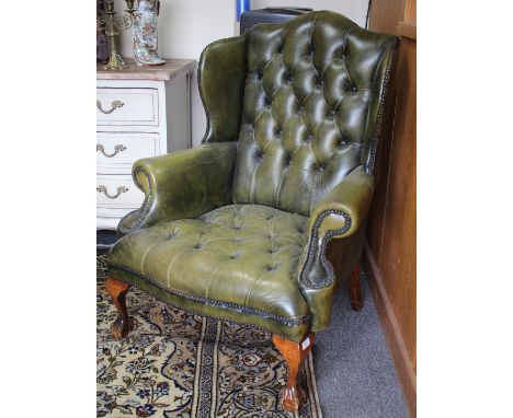 A GREEN LEATHER BUTTON UPHOLSTERED WING BACK ARMCHAIR with a studded edge and claw and ball feet 80cm wide 
