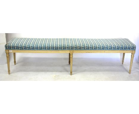 AN ANTIQUE CREAM PAINTED LONG, LOW OVERSTUFFED UPHOLSTERED STOOL with six fluted tapering legs 201cm long x 48cm high 