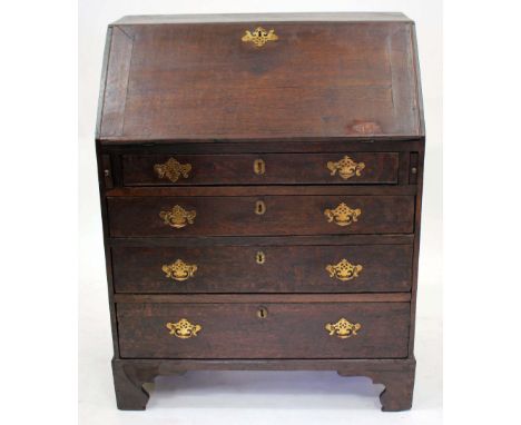 A GEORGE III OAK BUREAU the fall front opening to reveal pigeon holes and drawers all above four long drawers, all raised on 