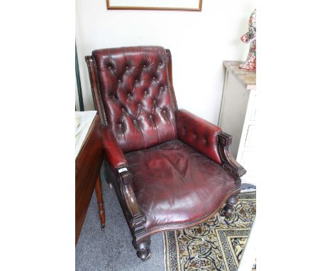 AN EARLY VICTORIAN MAHOGANY FRAMED OX BLOOD RED LEATHER BUTTON BACK UPHOLSTERED ARMCHAIR with turned front feet and brass cas