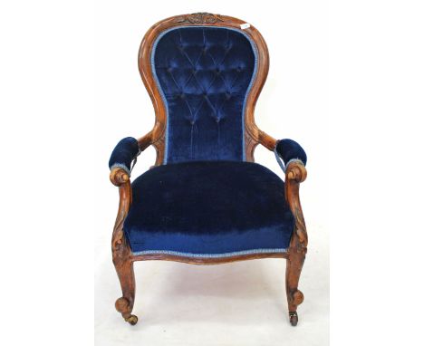 A VICTORIAN WALNUT OPEN ARMCHAIR with carved cresting rail to the shaped button upholstered back, with overstuffed upholstere