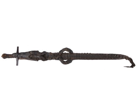 λ An East African sword (kaskara), cruciform hilt with iron cross guard, the scabbard formed from the preserved skin, limbs a