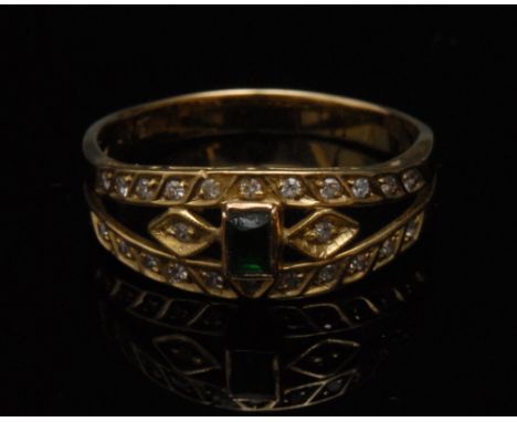 A diamond and emerald dress ring, central rectangular baguette cut emerald, set within an open framework encrusted with twent