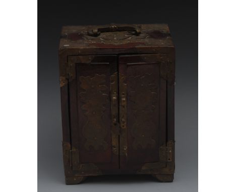 A Chinese padouk wood table cabinet, swing carrying handle above a pair of doors enclosing three drawers, applied overall wit