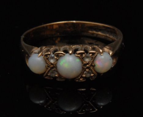 An opal and diamond seven stone dress ring, three round cabochon opals separated by two pairs of diamond chips, 9ct gold shan