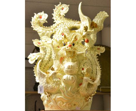 A Chinese ceramic table lamp, modelled with a ferocious dragon surmounted by pheasants and peacocks, the ivory ground picked 