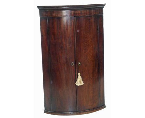 George III mahogany bow-front corner cupboard, molded cornice above two doors opening to reveal three fixed shelves, lower sh