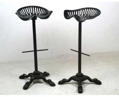 A pair of cast iron tractor seats made into bar stools, 40 by 33 by 86cm high. 