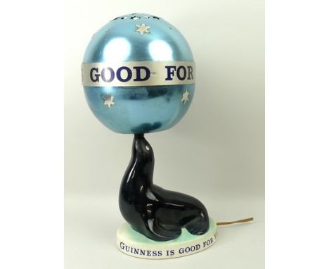 A Carlton ware Guinness advertising table lamp in the form of a seal with the original spinning globe shade and inscribed Gui