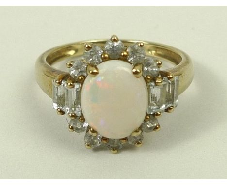 A 9ct gold and opal ring in a surround of brilliant and emerald cut zircons, size R, 2.9g.