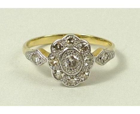 A 1930's 18ct gold and platinum unmarked cluster ring, set with nine diamonds in flower formation, each shoulder set with sin