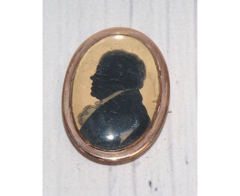 An early 19th century silhouette miniature portrait on paper, yellow metal brooch mount (untested), 3.5 x 2.5 cm overall