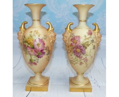 A pair of late 19th Century Royal Worcester porcelain ovoid 2-handled pedestal vases with face mask mount, on square bases, h