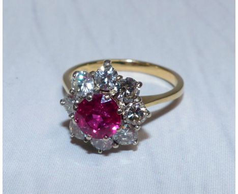 A yellow metal dress ring with central ruby simulant surrounded by 8 diamonds in cluster setting, marks worn, test as 18 cara