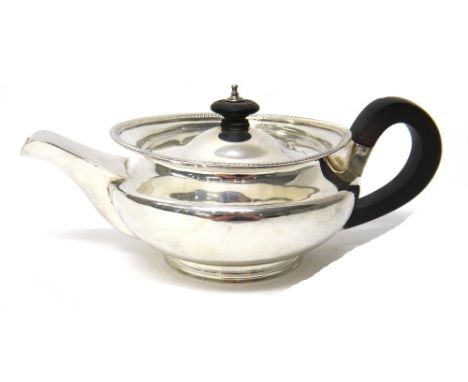 A George III silver teapot, of squat circular form, with later black fittings and with a gadrooned rim, maker R & S Hennell, 