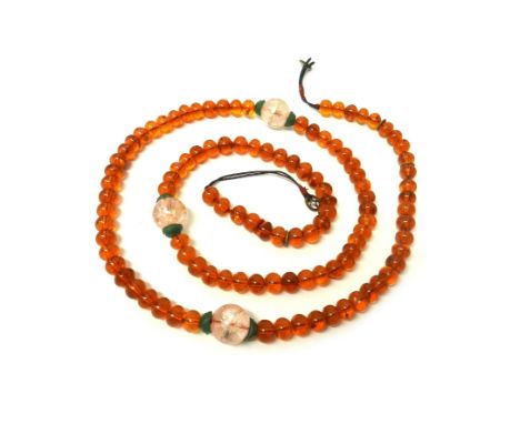 A carved jade Oriental pendant, a carved pale nephrite rectangular plaque, a translucent reconstituted amber bead necklace, s