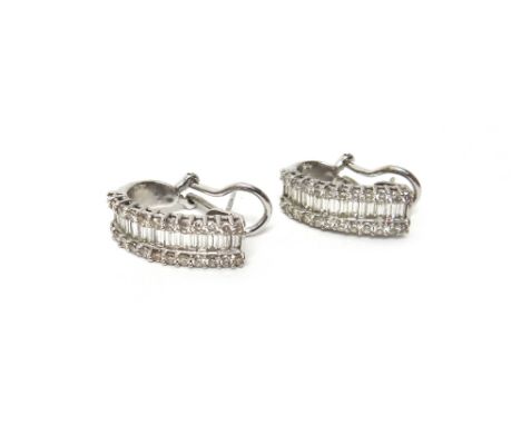 A pair of white gold and diamond set earclips, each designed as a row of baguette diamonds at the centre, between two rows of