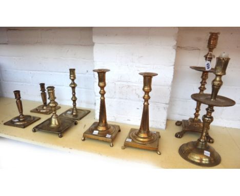 A Continental brass candlestick, early 19th century, with wide octagonal drip pan over a tapering square base and lion paw fe