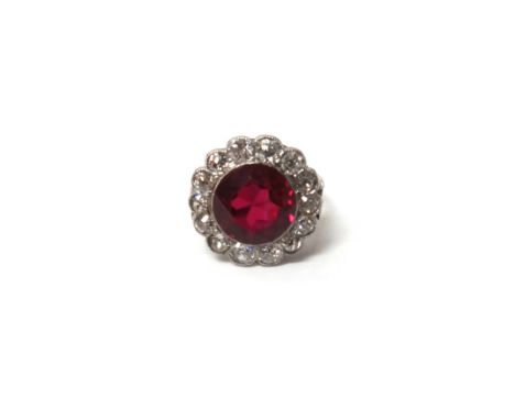 A white gold and platinum, diamond and synthetic ruby set cluster ring, mounted with the circular cut synthetic ruby at the c