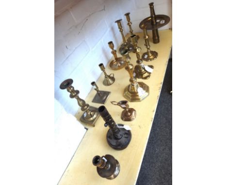 Eleven 18th century and later brass candlesticks, a brass chamber stick and a wrought iron and oak adjustable candlestick. Th