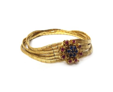A gold, sapphire and ruby set bracelet, designed as six rows of baton shaped links, having a textured finish, on a sapphire a