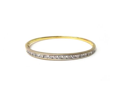A gold and diamond set oval hinged bangle, mounted with a row of twenty circular cut diamonds graduating in size to the centr