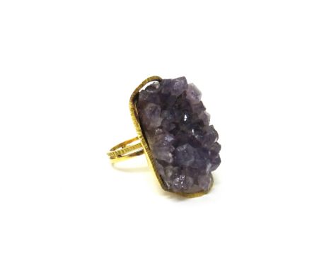 A gold ring, claw set with a piece of natural amethyst crystal, the twin shank with a partly textured design, ring size M, wi