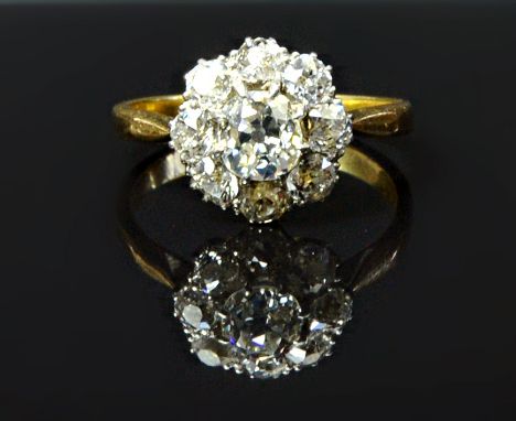 A gold and diamond set nine stone cluster ring, claw set with the principal cushion shaped diamond at the centre, in a surrou