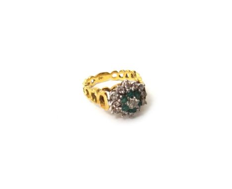 An 18ct gold, emerald and diamond set cluster ring, mounted with the principal circular cut diamond at the centre, in a surro