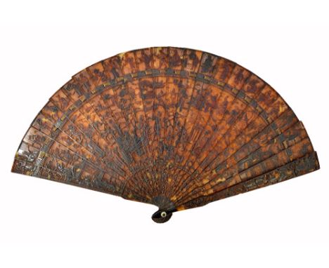 A Canton tortoiseshell fan, 19th century, carved all over with Oriental figures (a.f), the stick guard 19cm long. Illustrated