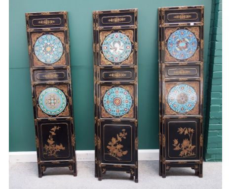A 20th century Chinese black lacquer six fold draught screen, each section mounted with two circular enamel panels, 264cm wid
