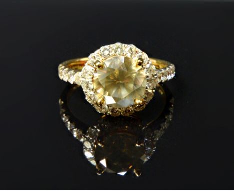 A gold ring, claw set with the principal circular cut fancy yellowish brown diamond at the centre, in a surround of small cir