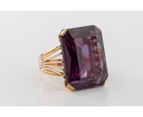 the step-cut amethyst to a yellow metal mount with split shoulders, ring size K, unmarked.