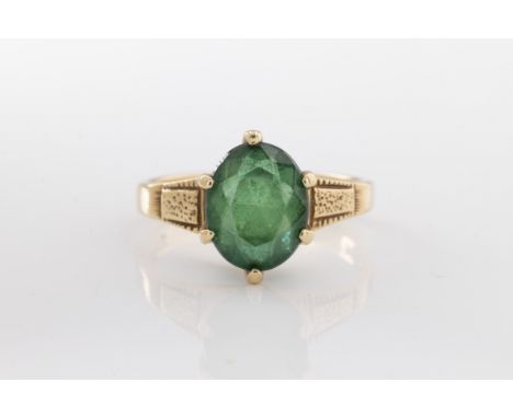 the oval-cut green stone, six-claw set, to a 10ct yellow gold band with engraved shoulders, ring size K 1/2.