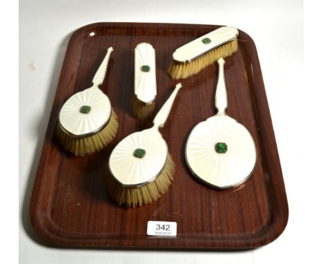 A silver and enamel dressing table set comprising of a hand mirror and four brushes 