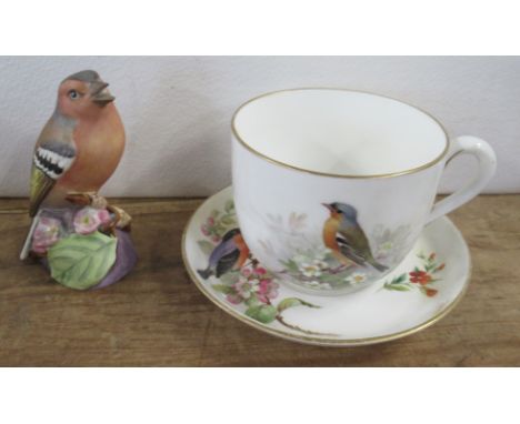 A Royal Worcester cup and saucer, decorated with birds by Powell, together with a Royal Worcester model of a Chaffinch