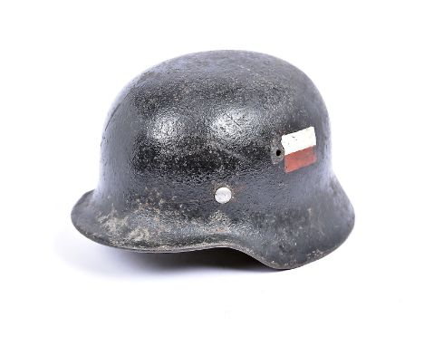 A WWII period German helmet, the black painted helmet with hand painted red and white flag decal to either side, missing line