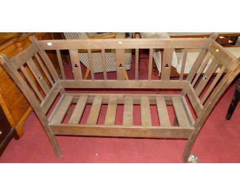 An Arts &amp; Crafts beech slatback twin bench settle, with three leaf clover pierced detail and of slatted construction, w.1